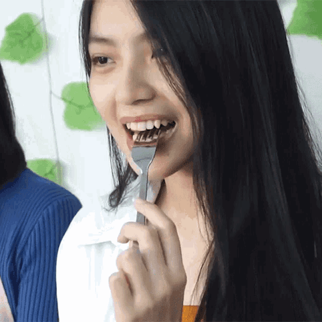 a woman is holding a silver fork in her mouth and smiling
