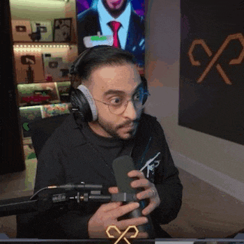 a man wearing headphones is holding a microphone in front of a computer screen .