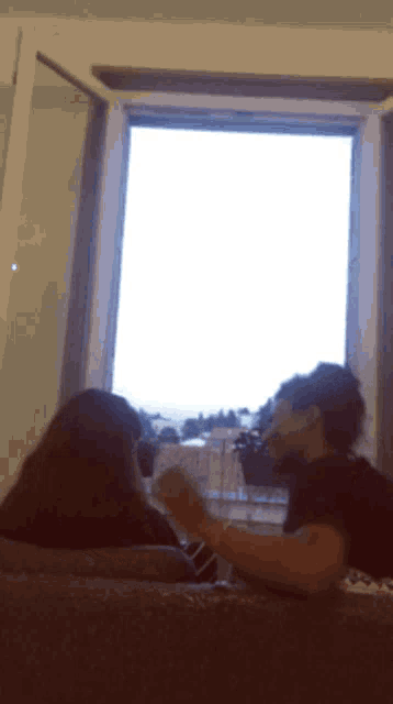 a woman sits on a couch in front of a large window