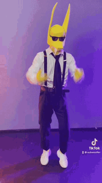 a man wearing a yellow mask and suspenders is dancing on a stage .