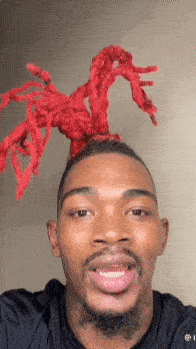 a man with red dreadlocks on his head is smiling for the camera