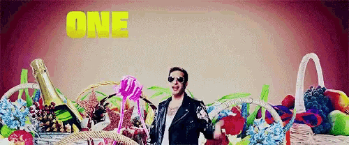 a man in a leather jacket is surrounded by baskets of fruit and flowers with the word one in yellow