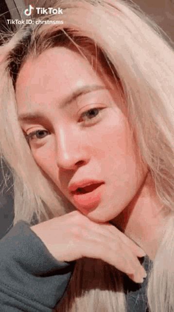 a woman with blonde hair and blue eyes is looking at the camera .