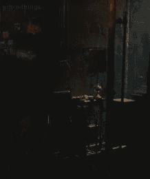 a woman is holding a candle in her hand in a dark room