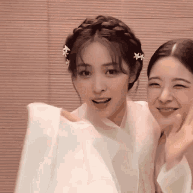 two women are posing for a picture and one has flowers in her hair .