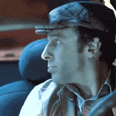 a man wearing a hat is sitting in a blue car