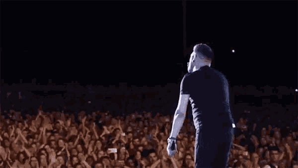 a man in a black shirt is standing on a stage in front of a crowd of people .