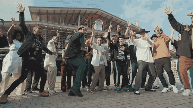 a large group of people are dancing in front of a building that says ' l' avenir ' on it