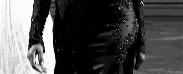 a black and white photo of a woman in a black dress standing on a stage .
