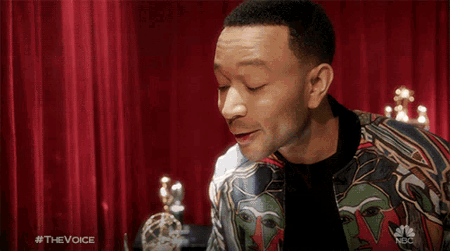 a man is kissing a trophy in front of a red curtain that says the voice