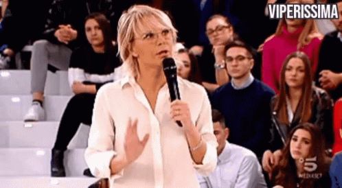 a woman is standing in front of a crowd holding a microphone .