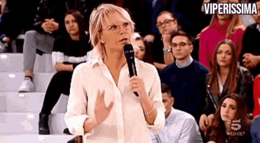 a woman is standing in front of a crowd holding a microphone .