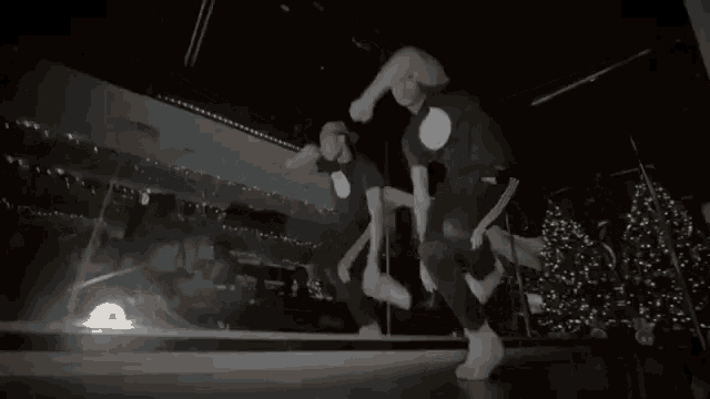a man is dancing in front of a mirror in a dark room with christmas trees in the background .
