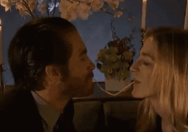 a man and a woman are kissing in front of a window with candles .