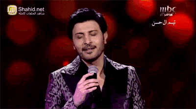a man singing into a microphone with shahid.net on the bottom