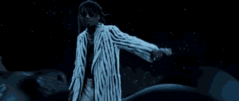 a man in a striped jacket and sunglasses is dancing in the dark .