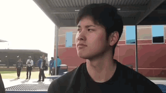 a young man is standing in front of a red building and looking at the camera .