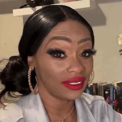 a woman with red lipstick and gold hoop earrings is making a funny face .