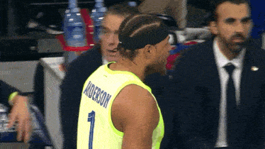 a basketball player wearing a yellow jersey with the name anderson on the back