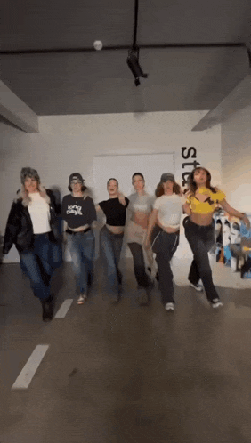 a group of women are dancing in a room with a sign on the wall that says studios