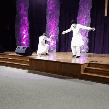 two men are dancing on a stage with purple lights