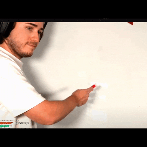 a man wearing headphones is pointing at something on a white board with a samsung monitor in the background