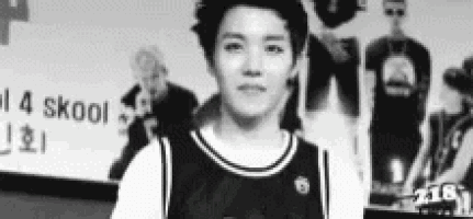 a black and white photo of a young man wearing a basketball jersey