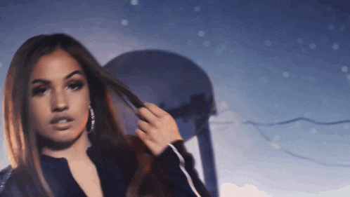 a woman in a black jacket holds her hair in her hand