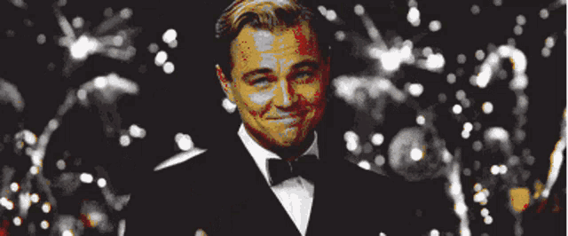 a man in a tuxedo and bow tie smiles in front of a crowd