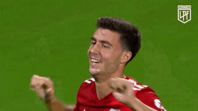 a soccer player wearing a red adidas jersey is smiling