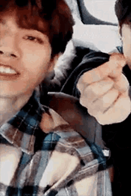 a man in a plaid shirt is pointing at another man .