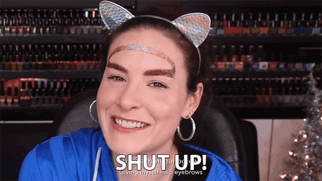 a woman wearing a cat ear headband and a blue shirt says shut up