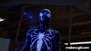 a man in a spiderman suit is standing in a dark room with a make a gif.com link below him
