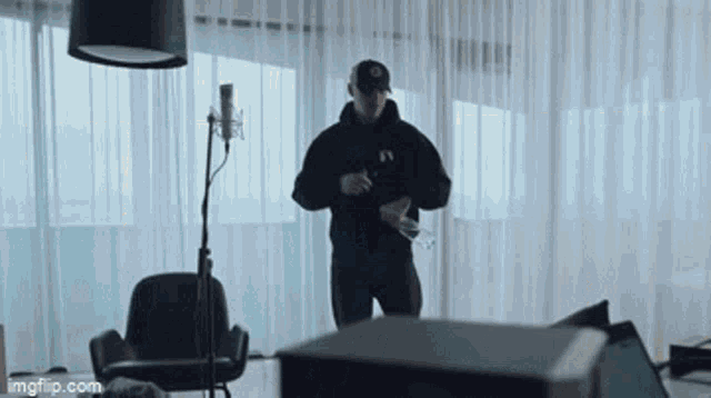 a man in a black hoodie is standing in front of a microphone ..