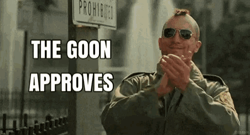 a man wearing sunglasses and a jacket is clapping his hands in front of a sign that says `` the goon approves `` .