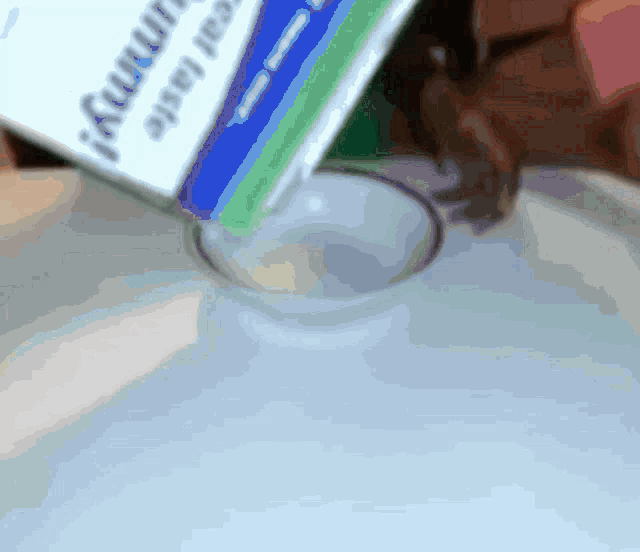 a carton of yogurt is being poured into a cup