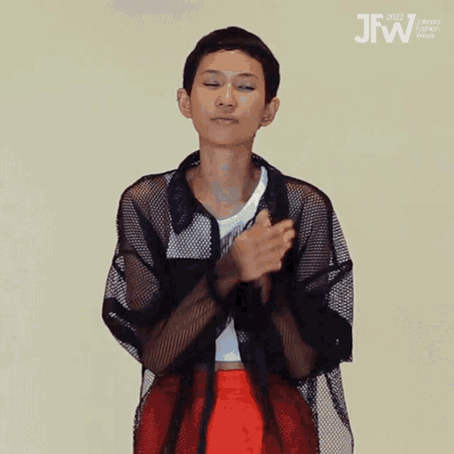 a woman is clapping her hands in front of a sign that says jfw 2021