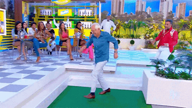 an elderly man is dancing on a stage in front of a crowd of people .