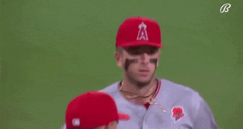 two baseball players wearing red hats are standing next to each other on a baseball field .