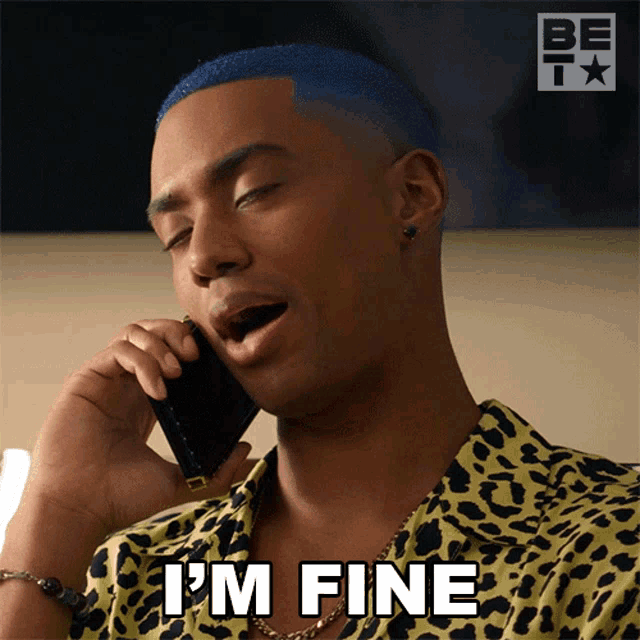 a man with blue hair is talking on a cell phone and saying i 'm fine