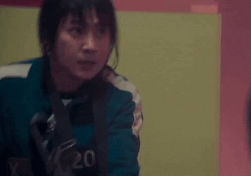 a woman in a blue jacket is holding a gun in her right hand