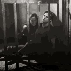 a man and a woman are sitting in a cage behind bars .