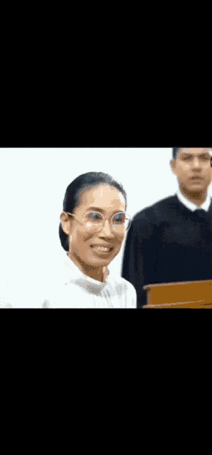 a woman wearing glasses is smiling in front of a man wearing a judge 's robe