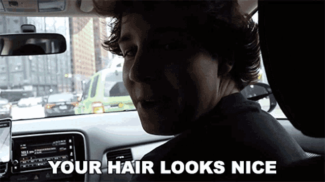a man in a car with the words " your hair looks nice " on the bottom