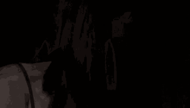 a woman is sitting in a dark room holding a glass cube with a light inside of it .