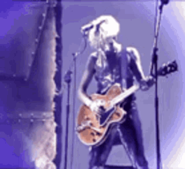 a woman is playing a guitar and singing into a microphone