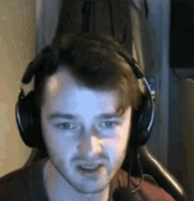 a man wearing headphones and a red shirt is looking at the camera