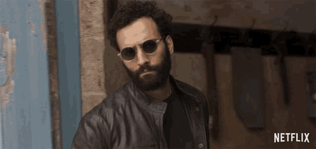 a man wearing sunglasses and a leather jacket with netflix written on the bottom right