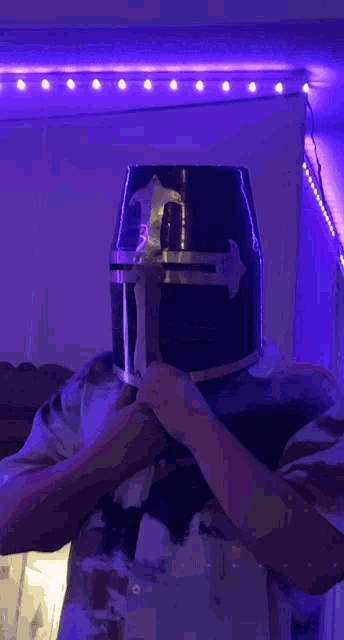 a man wearing a black knight 's helmet with a cross on it