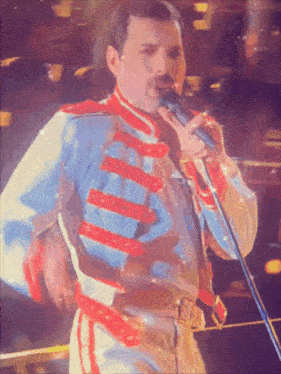 a man singing into a microphone wearing a blue and white uniform
